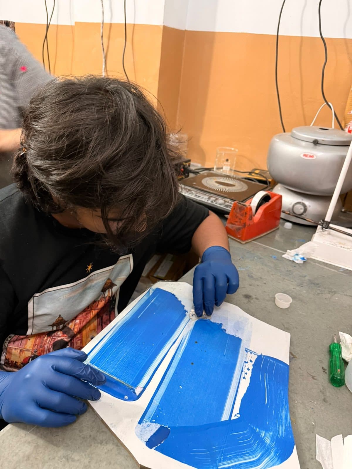 Student spreading a blue material film to dry