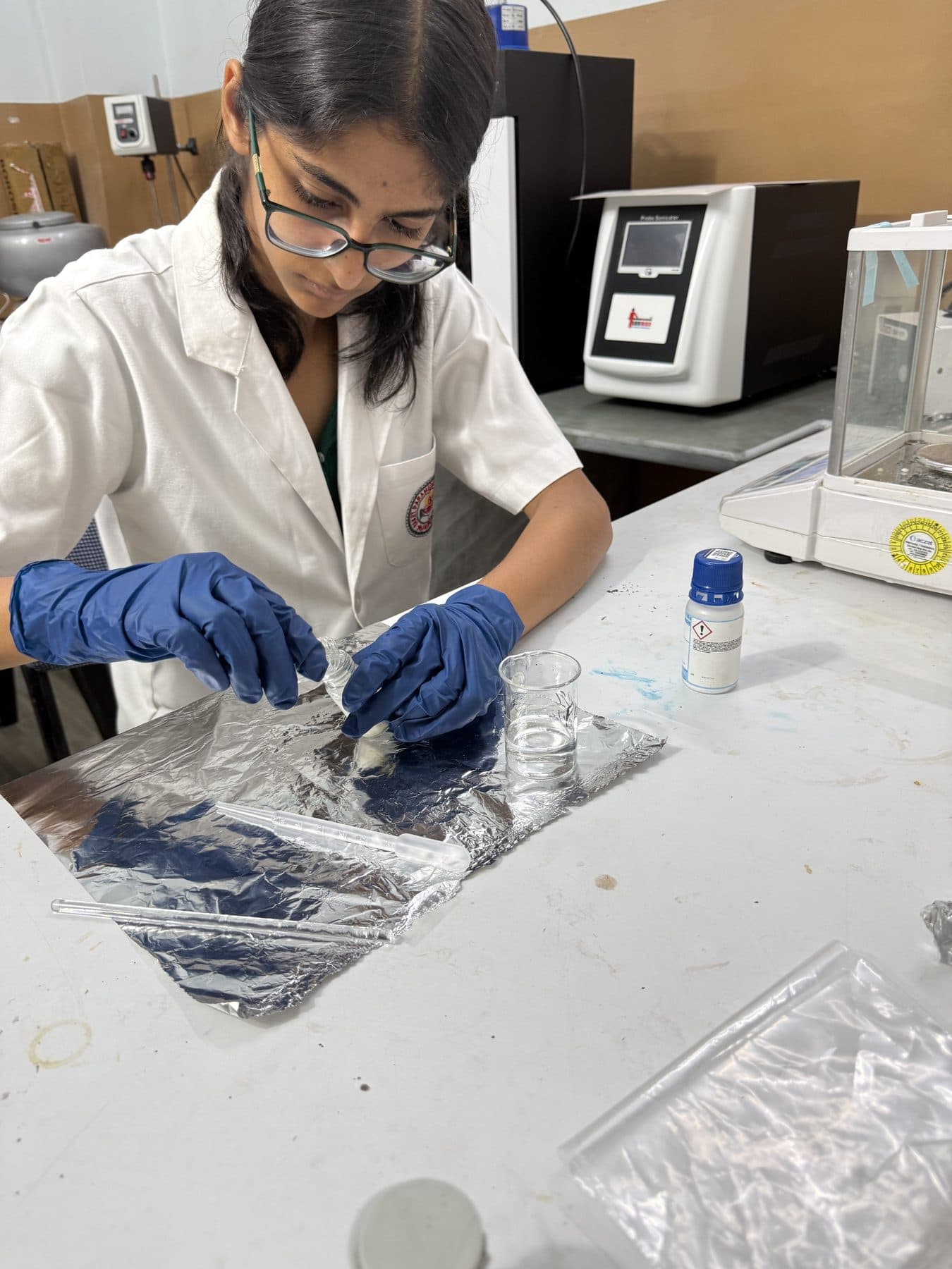 Student placing samples onto foil with tweezers