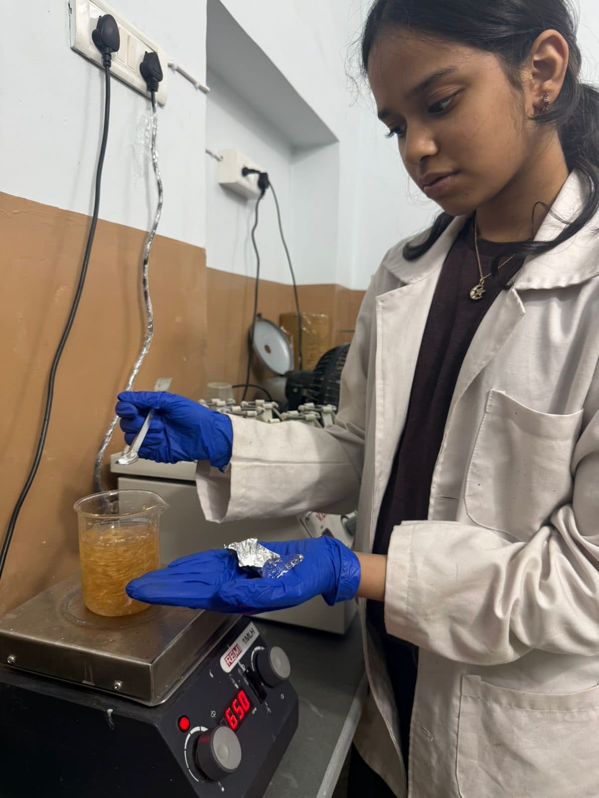 Student stirring an amber mixture on a hot plate