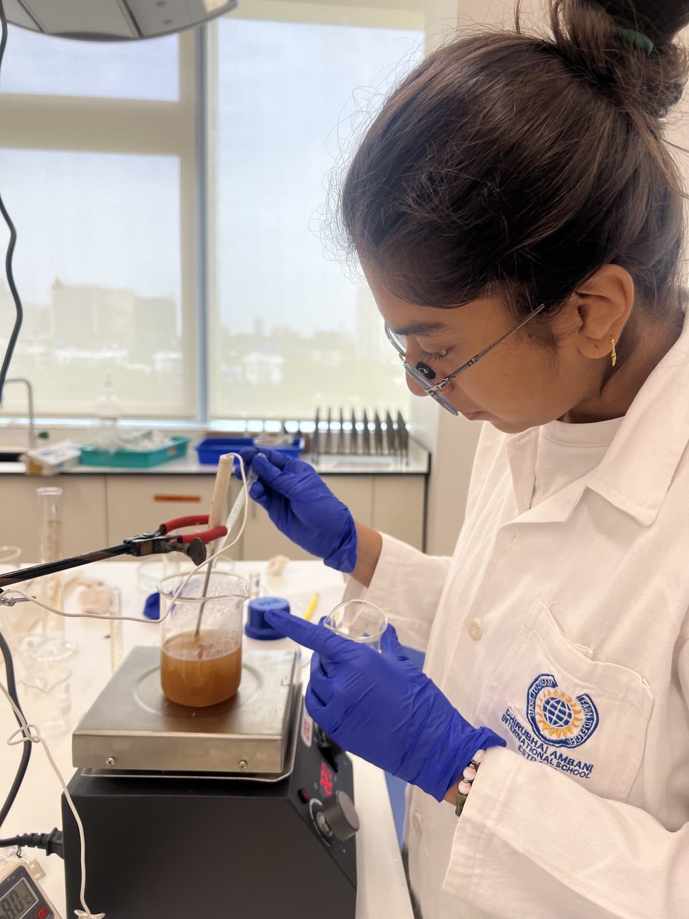 Student pipetting into an amber solution on a magnetic stirrer