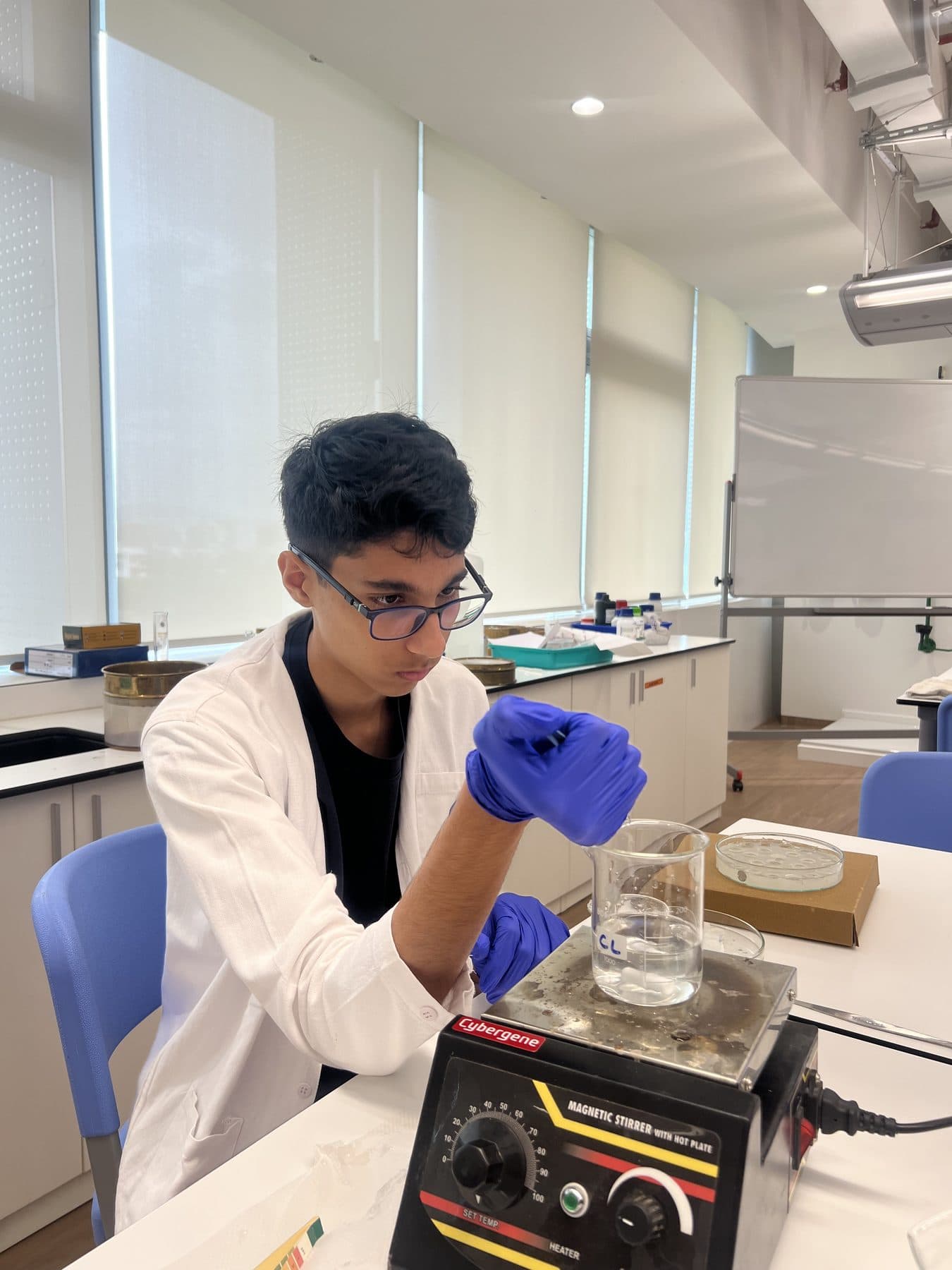 Student adjusting a beaker on a stirrer during an experiment