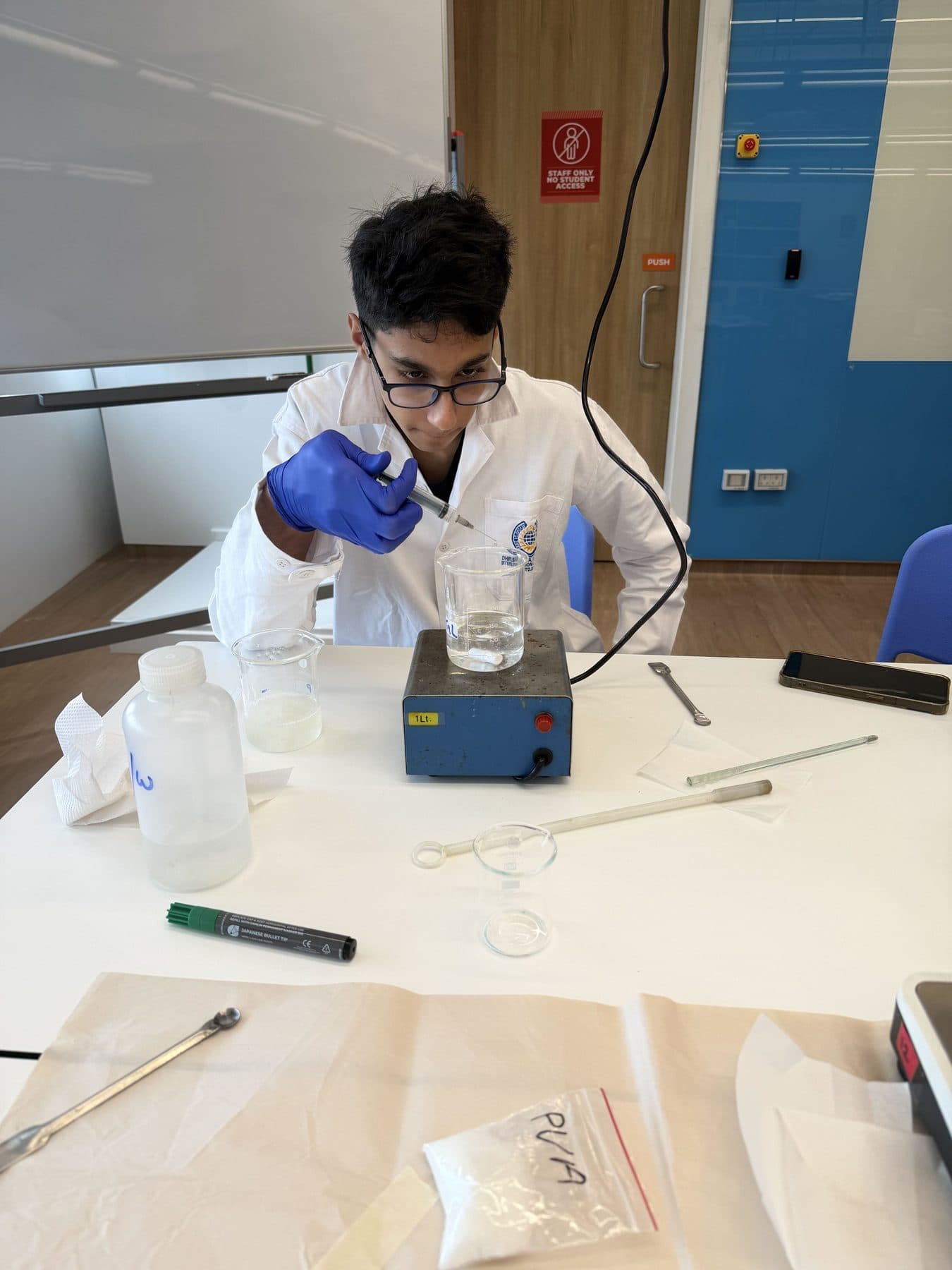 Student adding a reagent to a beaker on a magnetic stirrer